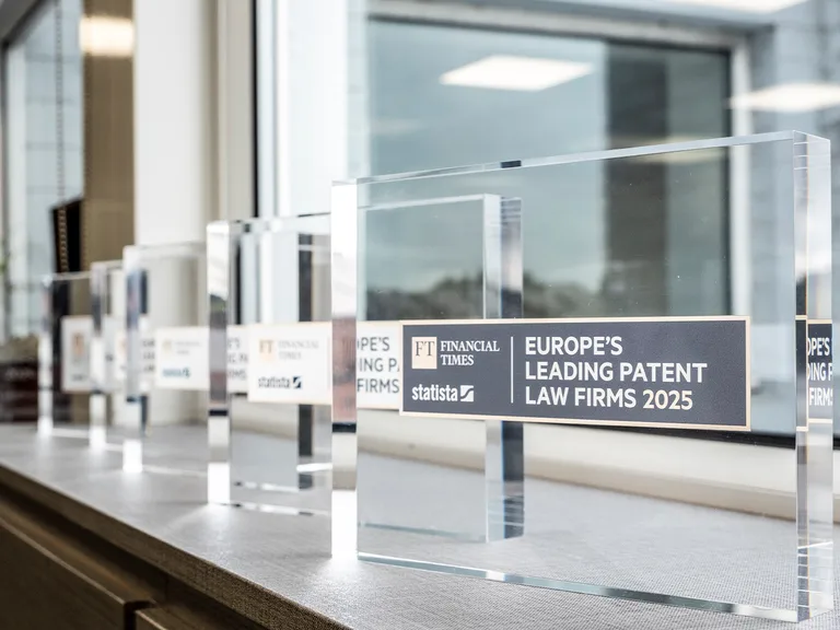Row of clear glass awards on a windowsill, plaques reading Europe’s Leading Patent Law Firms 2025 with FT Financial Times and Statista logos.