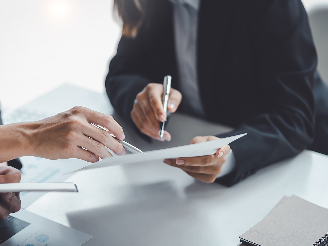Groupe de professionnels en costume signant et examinant des documents sur une table de bureau.