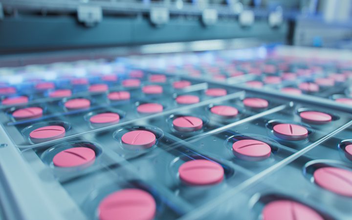 Multiple pink pills in blister packs on a medical tray.