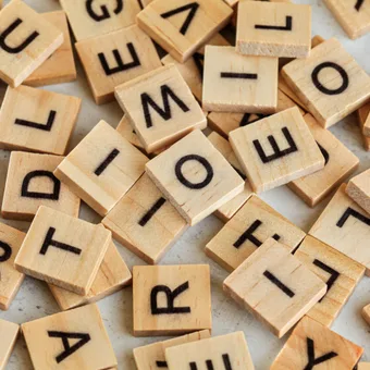 Scattered wooden letter tiles with black letters on a light background.